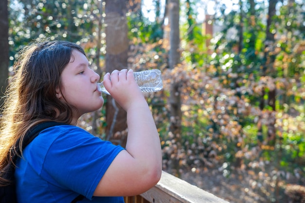 Menina bebendo água de uma garrafa no parque