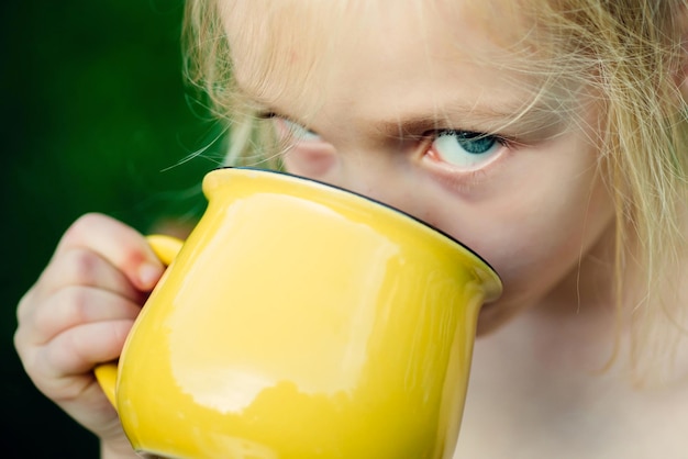 Menina bebendo algo suco de água ou leite momentos felizes criança despreocupada