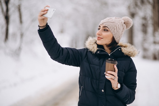 Menina bebendo café e fazendo selfie lá fora no inverno