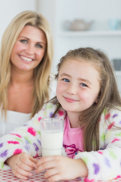 Menina bebendo um copo de leite com sua mãe