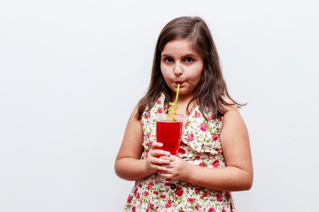 Menina bebendo um refresco de groselha com canudo divertido, fundo branco