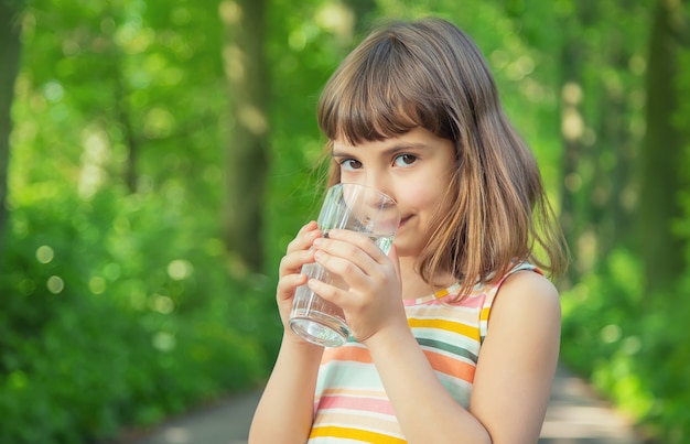 Menina beber água de um copo