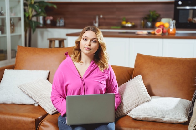 Menina bem gordinha segurando o laptop sobre os joelhos enquanto trabalhava à distância