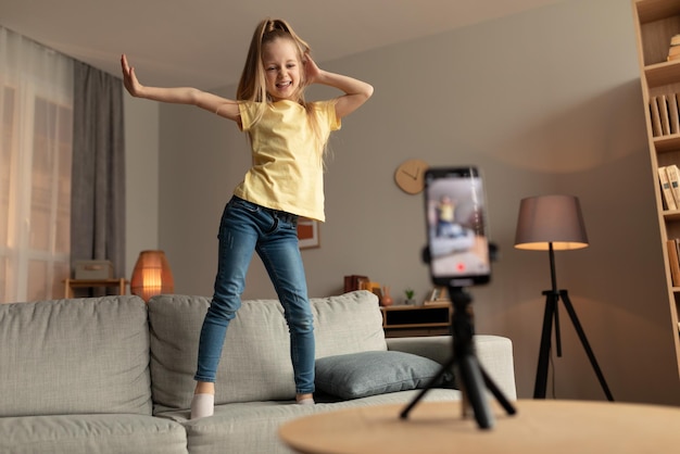 Menina blogueira alegre fazendo vídeo no smartphone em casa