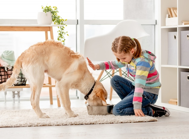 Menina bonita, alimentando o cão bonito