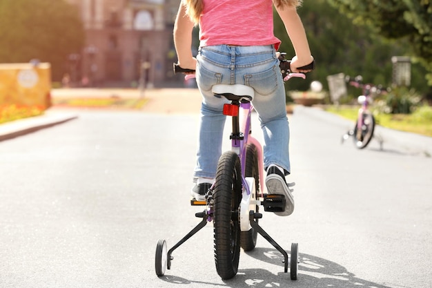 Foto menina bonita andando de bicicleta ao ar livre em um dia ensolarado