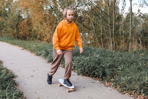 Menina bonita aprendendo a andar de skate ao ar livre no lindo dia de outono