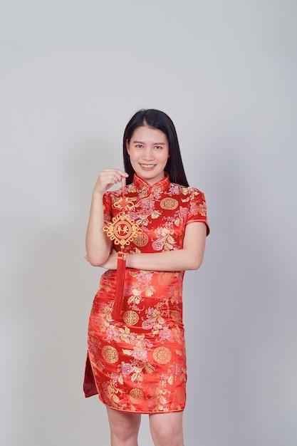 Menina bonita asiática com vestido tradicional chinês cheongsam ou qipao segurando foguete. conceito de ano novo chinês, modelo feminino isolado no fundo cinza do estúdio