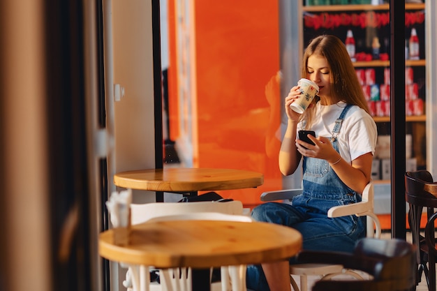 Menina bonita atraente jovem no café com café e telefone na manhã vigas