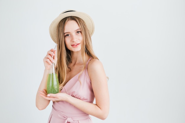 Menina bonita bebe uma bebida verde saudável com sementes de manjericão através de um tubo de metal reutilizável. O conceito de nutrição saudável, respeito pelo meio ambiente e desperdício zero. Tonificação.