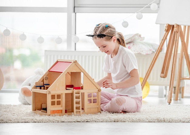 Menina bonita brincando com casa de bonecas