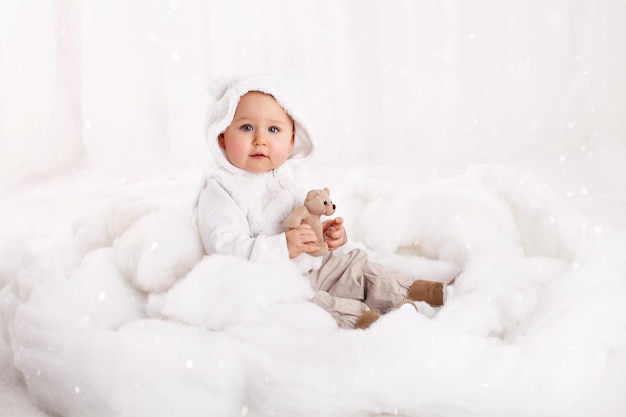 Menina bonita brincando com um ursinho de pelúcia em um algodão como neve artificial