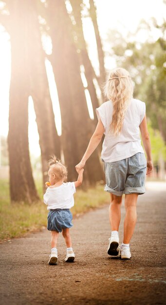 Menina bonita caminha no parque com sua mãe