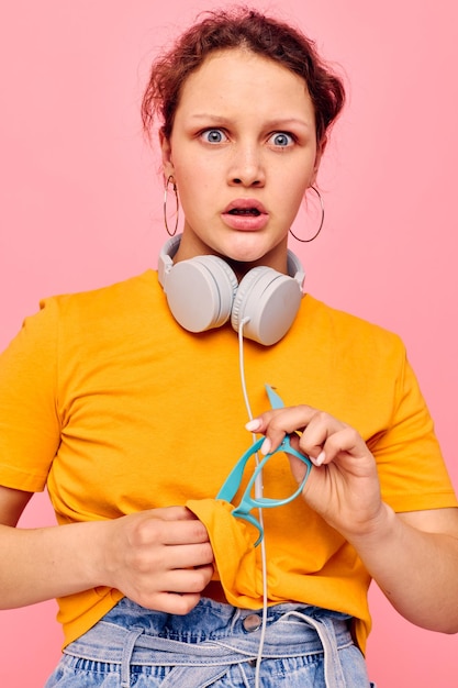 Menina bonita camiseta amarela fones de ouvido entretenimento música diversão fundos isolados inalterados