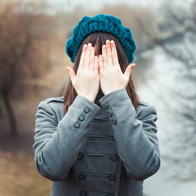 Menina bonita com as mãos sobre os olhos ao ar livre