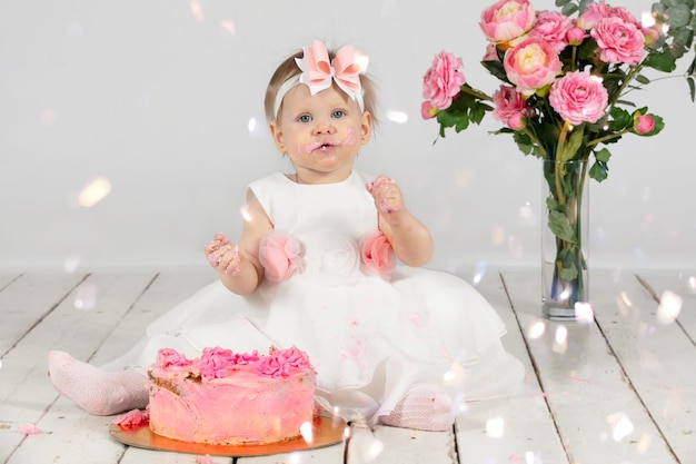 Menina bonita com bolos rosa está sentada no chão