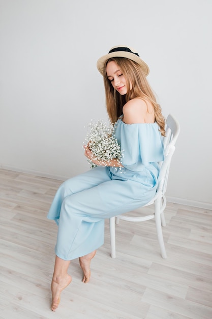 Foto menina bonita com cabelo comprido e chapéu posando com um buquê de flores brancas. tonificação.