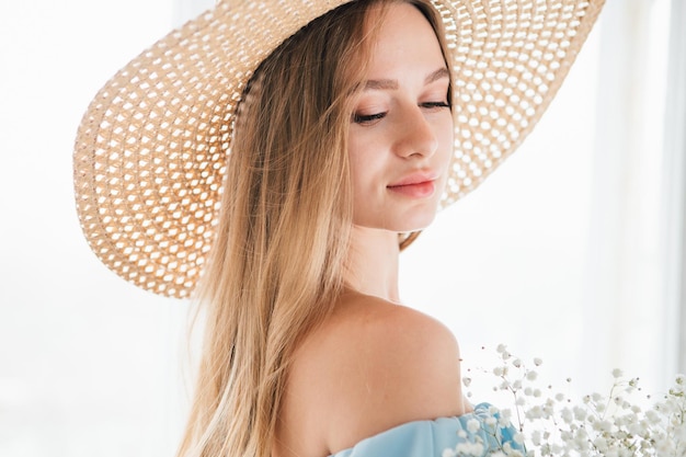 Menina bonita com cabelo comprido e chapéu posando com um buquê de flores brancas. Tonificação.