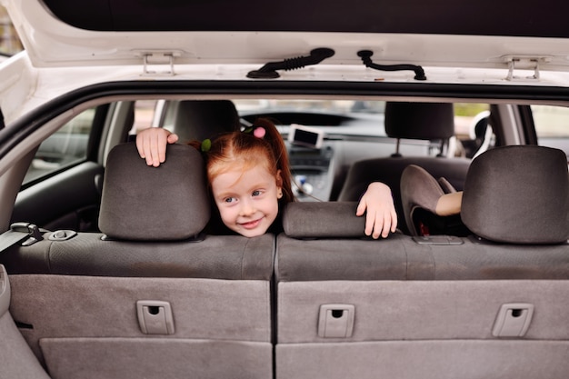 Menina bonita com cabelo vermelho sorrindo no interior de um interior de carro