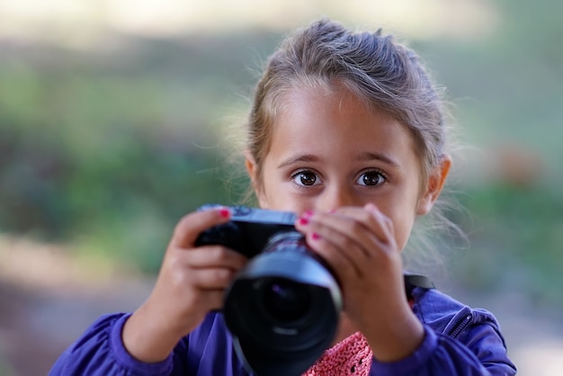 Menina bonita com câmera fotográfica tira fotos