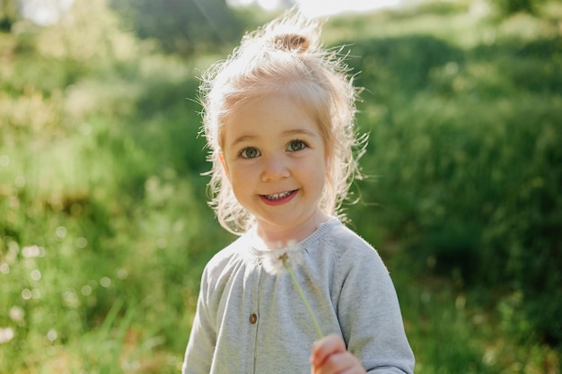 Foto menina bonita com dente-de-leão em fundo ensolarado de primavera