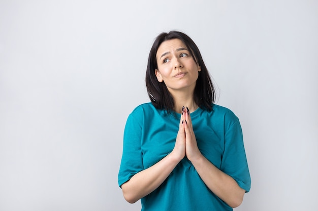 Menina bonita com expressão desamparada, pede ajuda, mantém as palmas das mãos pressionadas.