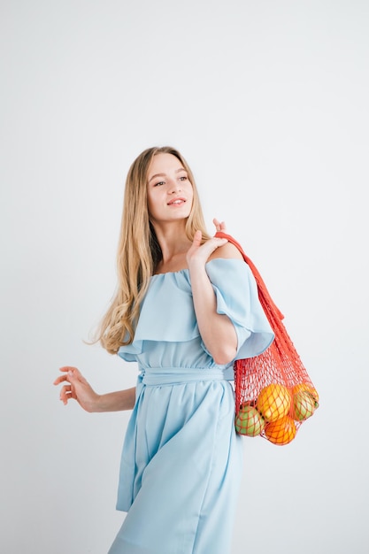 Menina bonita com frutas frescas em um saco de cordas. O conceito de desperdício zero. Tonificação.