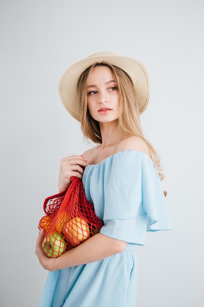 Menina bonita com frutas frescas em um saco de cordas. O conceito de desperdício zero. Tonificação.
