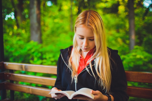 Menina bonita com livro na floresta de outono