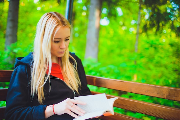 Menina bonita com livro na floresta de outono