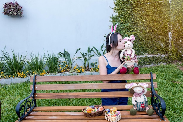 Menina bonita com orelhas de coelhinho da Páscoa no banco do jardim