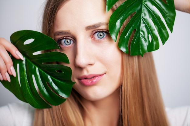 Menina bonita com pele saudável e planta verde