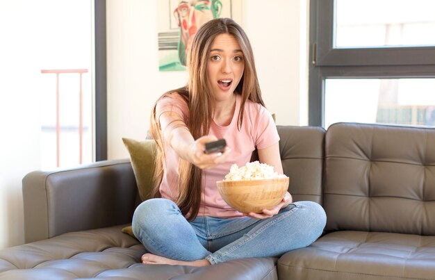 Menina bonita com pipoca assistindo a um filme em casa