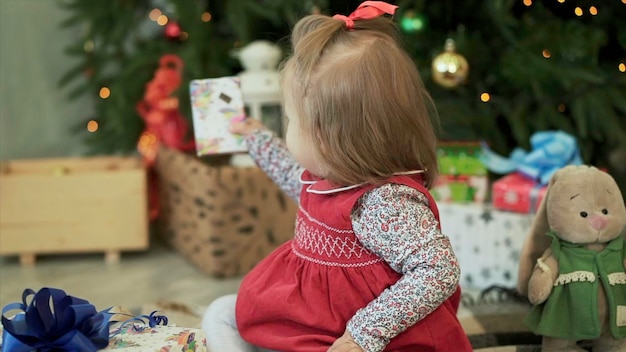 Menina bonita com presentes de Natal sentada perto da árvore de Natal em close-up