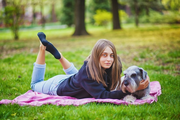 Menina bonita com seu cachorro Schnauzer no parque natural