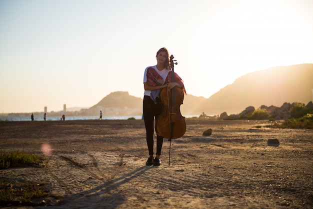 Menina bonita com seu violoncelo no exterior