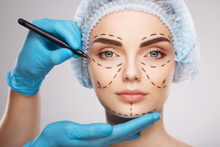 Foto menina bonita com sobrancelhas escuras, usando chapéu azul médico na parede, as mãos do médico usando luvas azuis desenhando linhas de perfuração no rosto, conceito de cirurgia plástica.