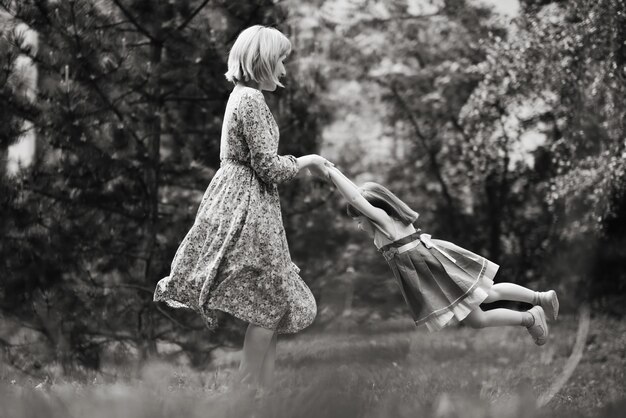 Menina bonita com sua mãe no passeio Mãe feliz circulando filha pequena na dança mãe ativa sua pré-escola criança engraçada menina fotografia preto e branco foco suave