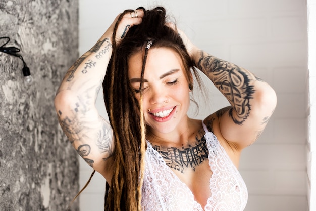 Menina bonita com tatuagens e dreadlocks, estilo moderno de casa