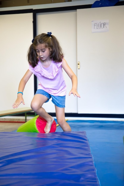 Menina bonita com tranças jogando no ginásio da escola.