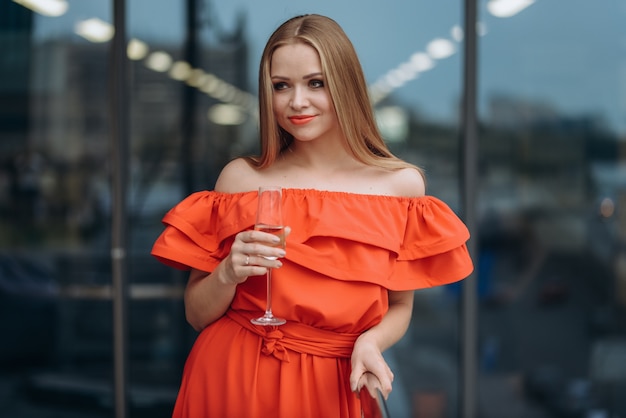 Menina bonita com um vestido vermelho com uma taça de champanhe