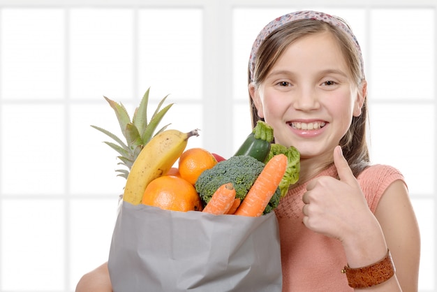 Menina bonita com uma sacola cheia de frutas e legumes