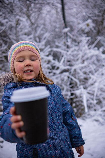 Foto menina bonita com uma xícara de chá e um boneco de gengibre em um dia de inverno nevado