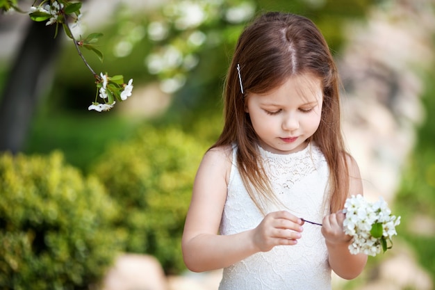 Menina bonita com vestido creme no jardim de flores