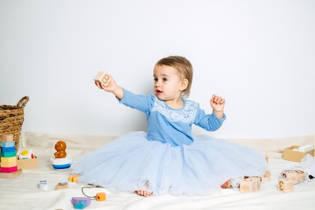 Menina bonita com vestido de princesa azul brincando com brinquedos em casa Vestidos infantis para baile e feriado de aniversário