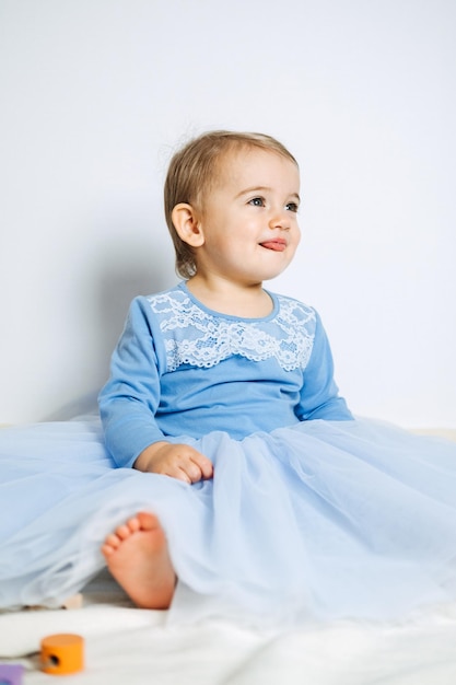 Menina bonita com vestido de princesa azul brincando com brinquedos em casa Vestidos infantis para baile e feriado de aniversário