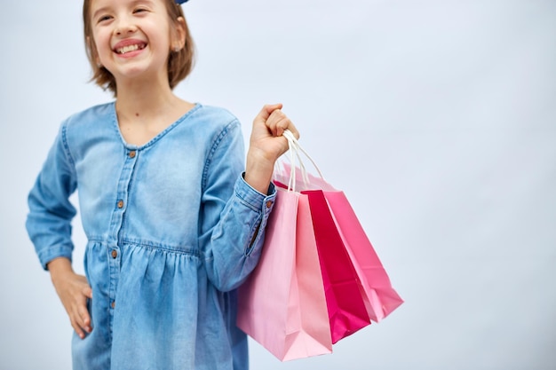 Menina bonita com vestido jeans casual, segure sacolas de compras cor-de-rosa na mão