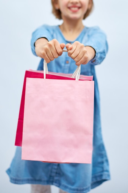 Menina bonita com vestido jeans casual, segure sacolas de compras cor-de-rosa na mão