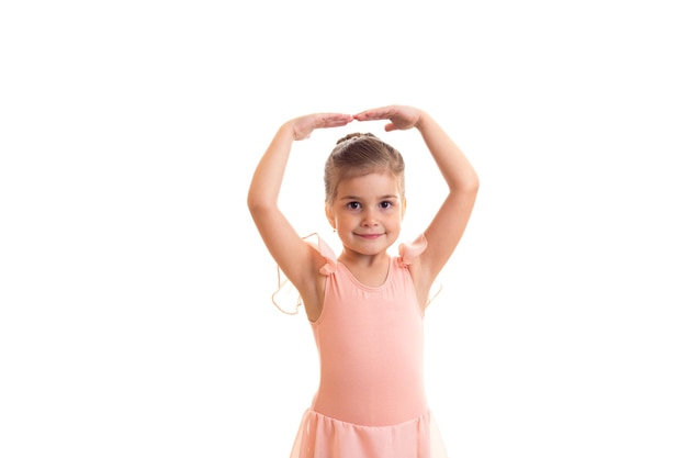 Menina bonita com vestido rosa dançando no fundo branco no estúdio