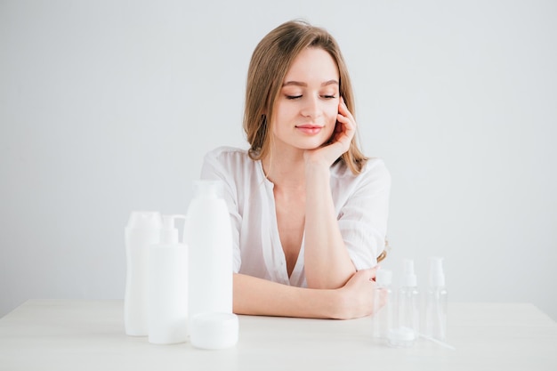 Foto menina bonita compara o tamanho de frascos de cosméticos para viagens para economizar espaço na mala. tonificação.